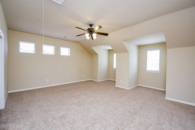 This expansive upstairs area features soft carpeting and unique recessed walls with windows that brighten the space—perfect for media, games, or creative endeavors. | Image 23