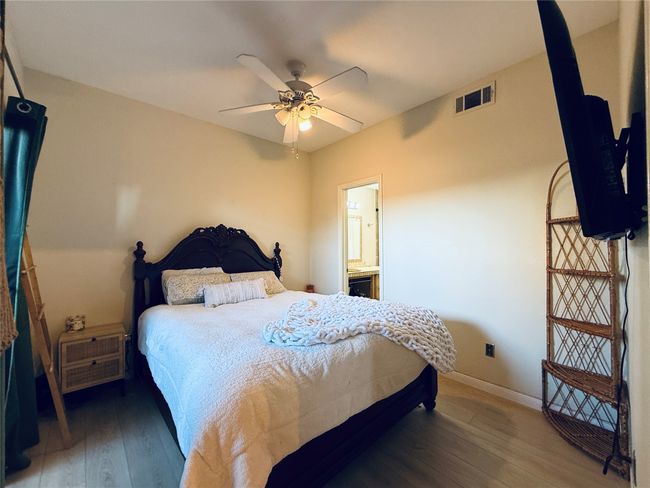Bedroom featuring visible vents, hardwood / wood-style floors, ensuite bathroom, ceiling fan, and baseboards | Image 12