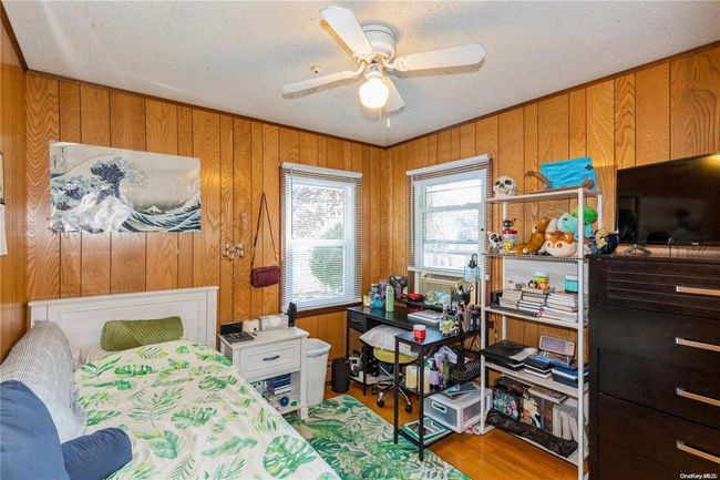 Bedroom featuring wood walls, wood finished floors, and multiple windows | Image 18