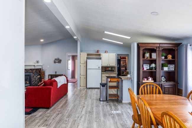 Dining room with a stone fireplace, light wood finished floors, recessed lighting, and lofted ceiling | Image 5