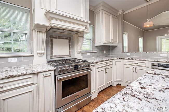 Kitchen featuring wood finished floors, stainless steel appliances, light stone countertops, and backsplash | Image 13