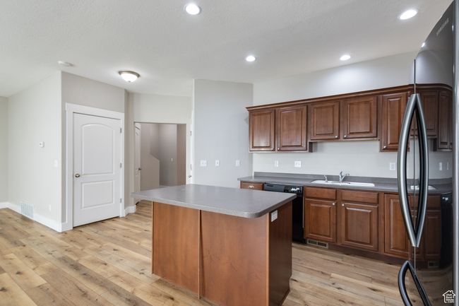 Kitchen with freestanding refrigerator, black dishwasher, light wood finished floors, a center island, and recessed lighting | Image 6