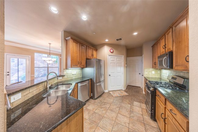 Kitchen with stainless steel appliances, a chandelier, tasteful backsplash, recessed lighting, and brown cabinets | Image 12