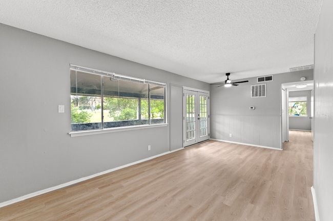 Spare room featuring wood finished floors, a ceiling fan, visible vents, and a textured ceiling | Image 4