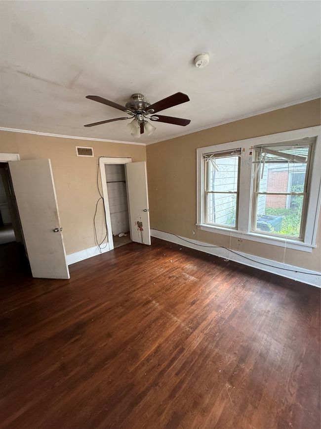 Unfurnished bedroom with dark wood-style floors, ornamental molding, and a ceiling fan | Image 8