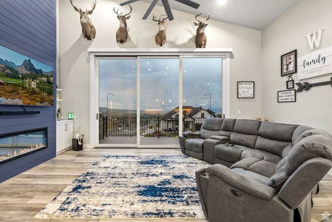 Living room featuring a large fireplace, wood finished floors, ceiling fan, and vaulted ceiling | Image 77