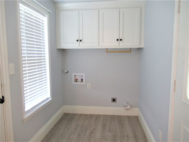 Washroom with washer hookup, light wood-type flooring, hookup for an electric dryer, baseboards, and cabinet space | Image 17