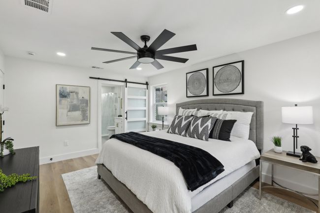 Bedroom with a barn door, wood finished floors, baseboards, visible vents, and recessed lighting | Image 12