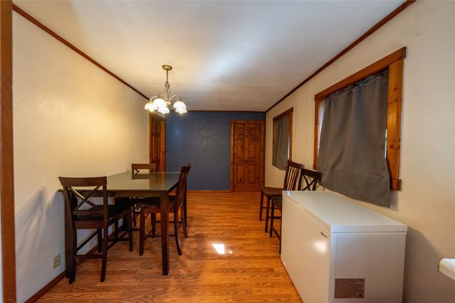 Dining room with light wood-style floors, crown molding, and a chandelier | Image 12