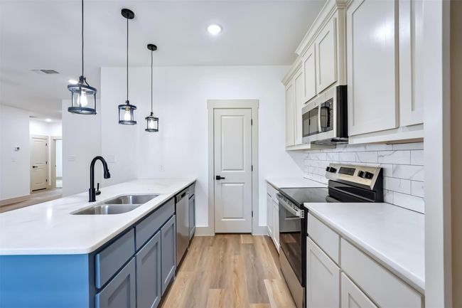 Kitchen featuring a peninsula, visible vents, appliances with stainless steel finishes, light countertops, and a sink | Image 5