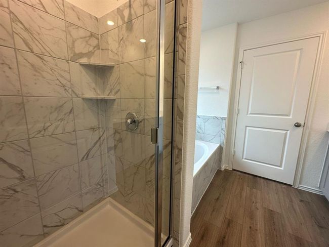 Bathroom with wood finished floors, a stall shower, and a garden tub | Image 25