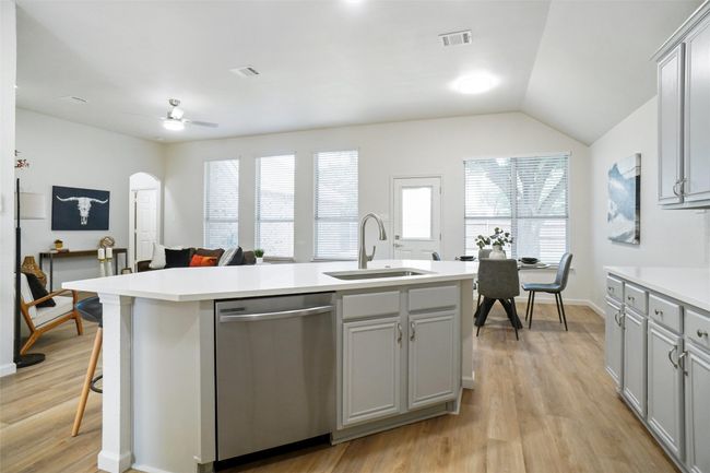 Kitchen featuring dishwasher, a sink, gray cabinets, light wood-type flooring, and light countertops | Image 7