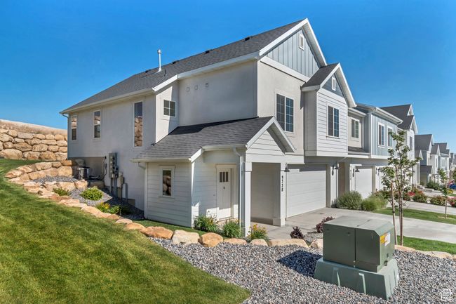 View of side of property with board and batten siding, an attached garage, driveway, a residential view, and a yard | Image 4