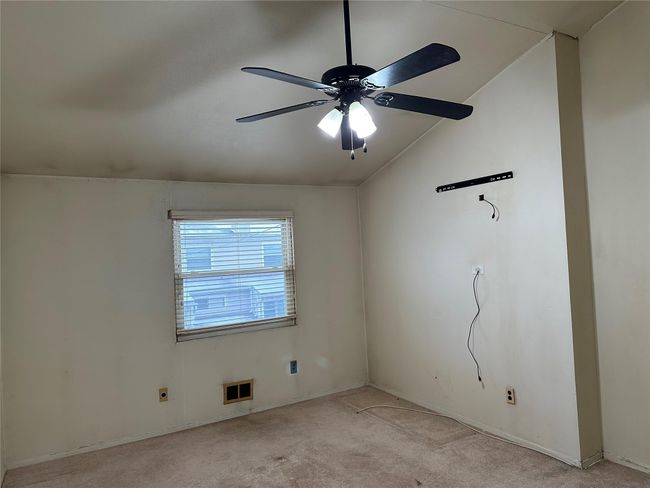 Empty room with light carpet, visible vents, a ceiling fan, and lofted ceiling | Image 7