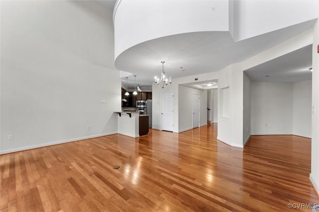 Unfurnished living room with baseboards, a chandelier, and light wood-style floors | Image 16