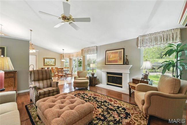 Living room with lofted ceiling, wood finished floors, ceiling fan, and a glass covered fireplace | Image 6