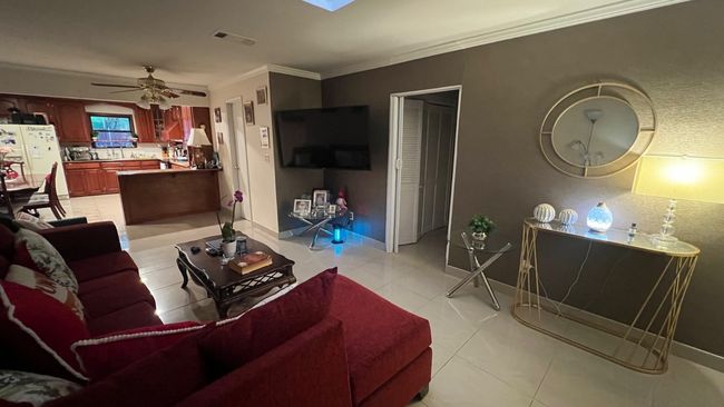 Living room featuring light tile patterned floors, ceiling fan, crown molding, and baseboards | Image 7