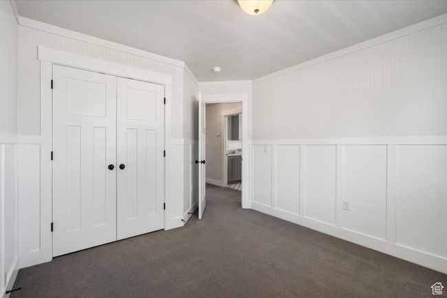 Unfurnished bedroom with a decorative wall, carpet flooring, a closet, and a wainscoted wall | Image 35