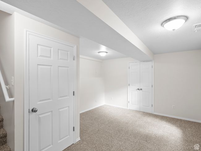 Basement featuring baseboards, carpet flooring, and a textured ceiling | Image 25