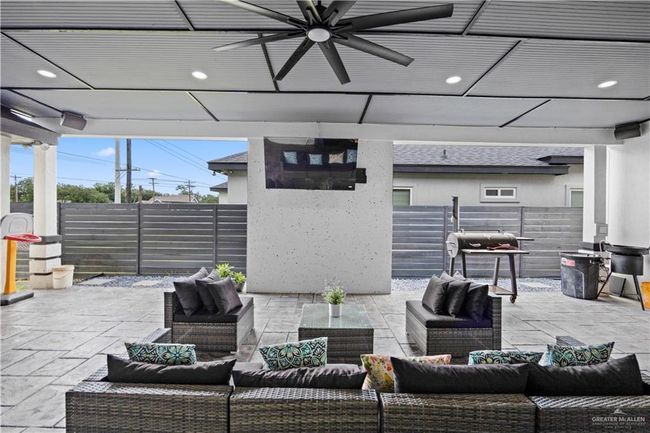 Fenced backyard featuring an outdoor hangout area, a ceiling fan, and a patio area | Image 6