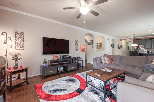 Living area featuring arched walkways, crown molding, dark wood finished floors, a ceiling fan, and baseboards | Image 11