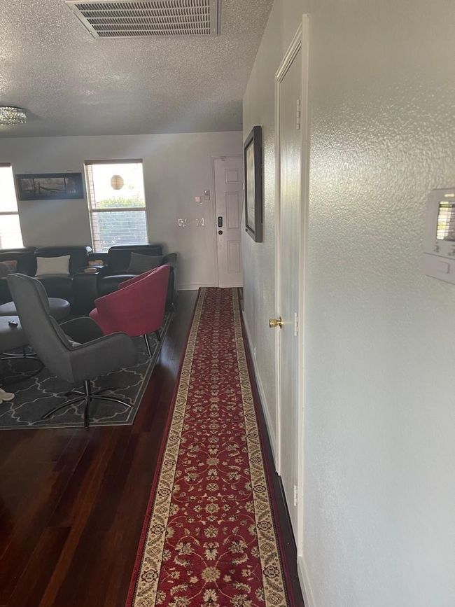 Corridor featuring wood finished floors, a textured ceiling, an office area, and baseboards | Image 7
