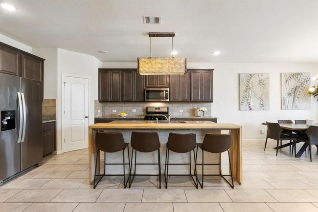 This sleek kitchen offers island seating and an open flow into the dining area and living room - perfect for entertaining. | Image 11