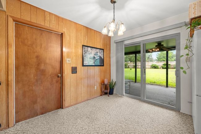 Doorway to outside featuring carpet floors, wood walls, and a chandelier | Image 14