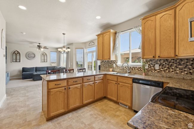 Kitchen with dishwasher, a peninsula, open floor plan, backsplash, and a chandelier | Image 16