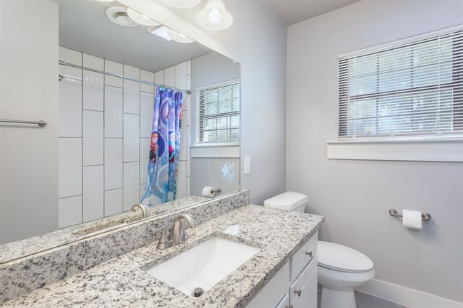 Bathroom featuring a shower with shower curtain, baseboards, toilet, and vanity | Image 21