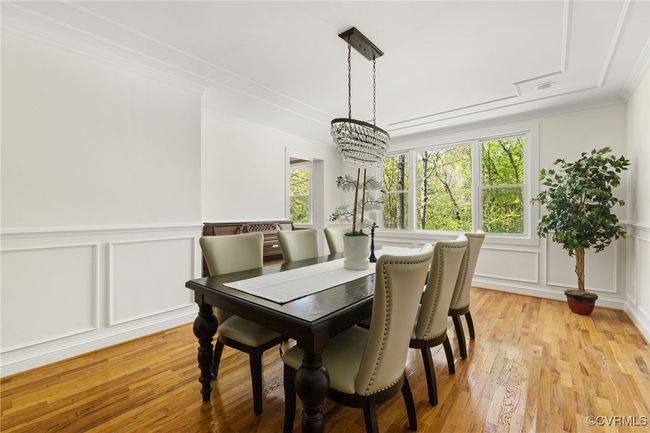 Elegant dining room featuring hardwood floors, crown molding, chair rail, wainscotting and updated chandelier. | Image 9