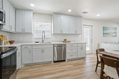 Kitchen with appliances with stainless steel finishes, decorative backsplash, light hardwood / wood-style floors, and sink | Image 3