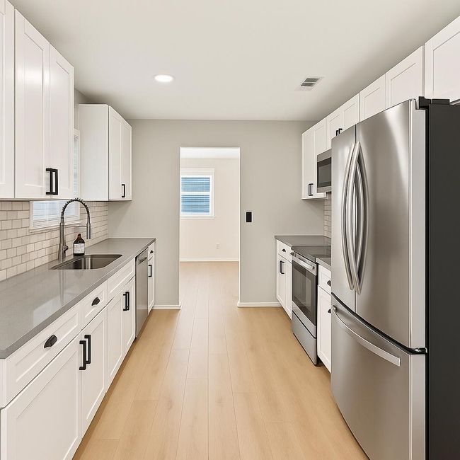 Kitchen featuring stainless steel appliances, a sink, backsplash, white cabinetry, and baseboards | Image 8
