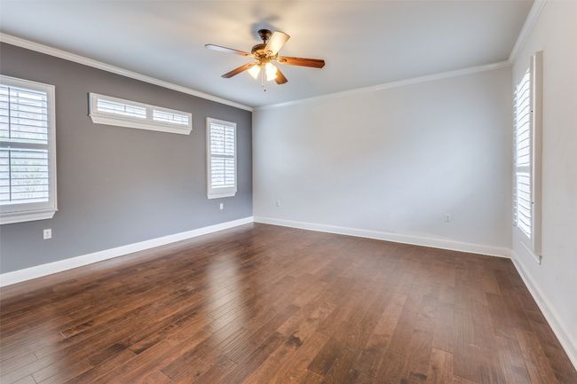 Unfurnished room with a ceiling fan, dark wood-style flooring, ornamental molding, and baseboards | Image 11