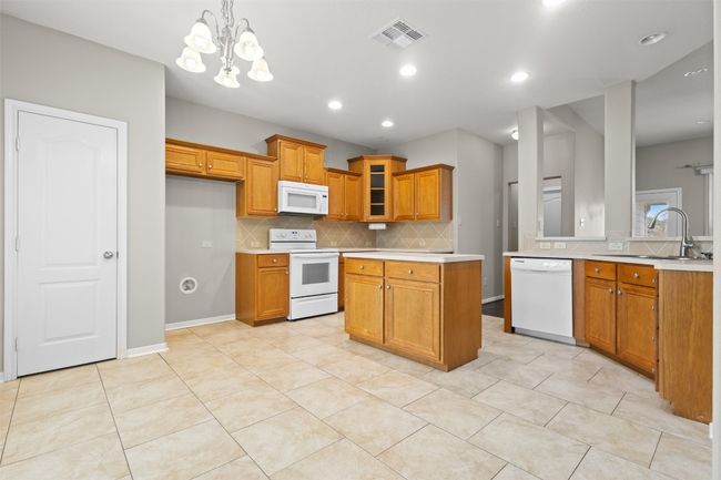 Kitchen featuring white appliances, light countertops, brown cabinetry, decorative backsplash, and recessed lighting | Image 11