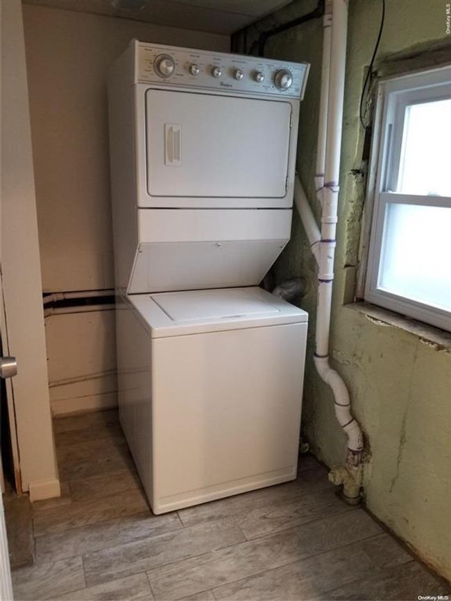 Washroom featuring stacked washer and clothes dryer and light wood-style floors | Image 18