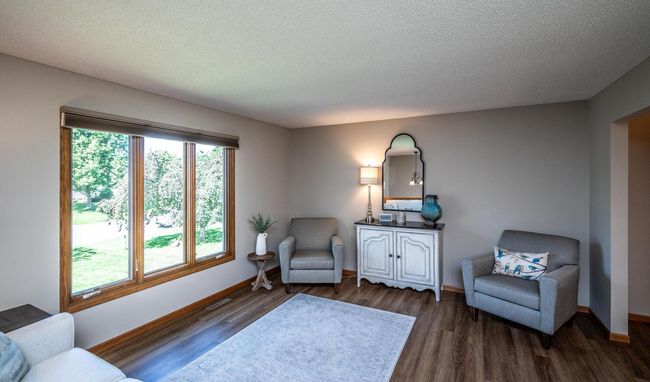 Living room with large windows to front. LVP flooring flows throughout the living room, dining room, kitchen, and upper level bedrooms. Six-panel doors on upper level, tasteful decor & custom window treatments throughout. | Image 5