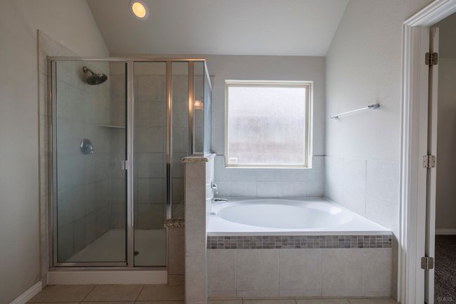 Bathroom featuring a stall shower, a garden tub, tile patterned flooring, and lofted ceiling | Image 13