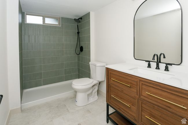 Bathroom featuring vanity, a tile shower, toilet, and baseboards | Image 9