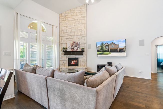 Living room with high vaulted ceiling, a stone fireplace, dark wood-style flooring, and a ceiling fan | Image 12