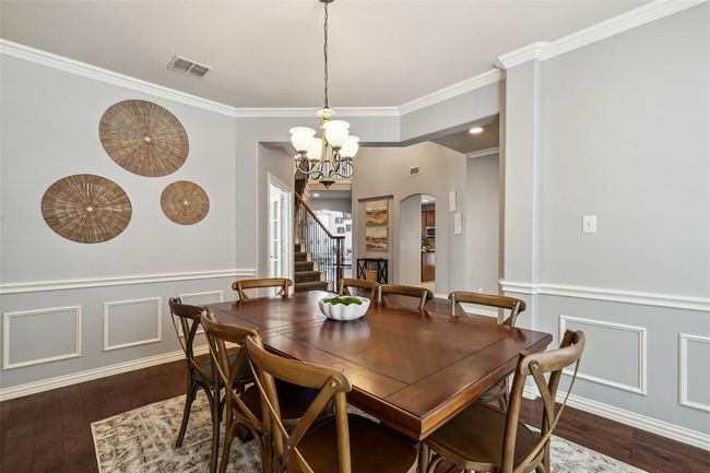 Dining space with dark wood-type flooring, a notable chandelier, and ornamental molding | Image 5