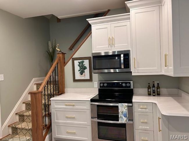 Kitchen featuring stainless steel appliances, light countertops, and white cabinetry | Image 9