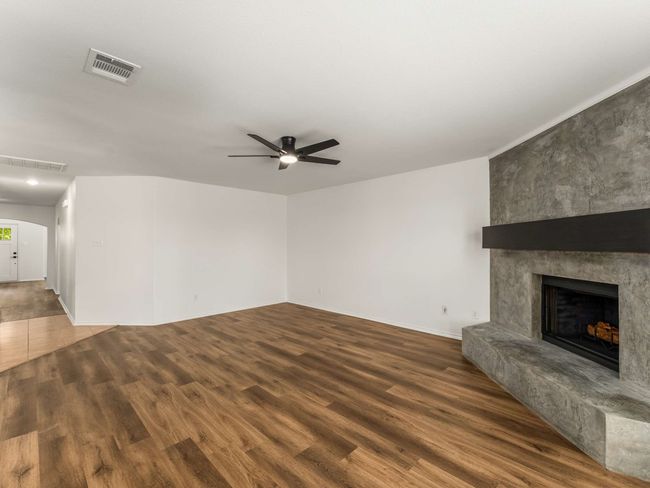 Unfurnished living room featuring a ceiling fan, wood finished floors, and a fireplace | Image 11