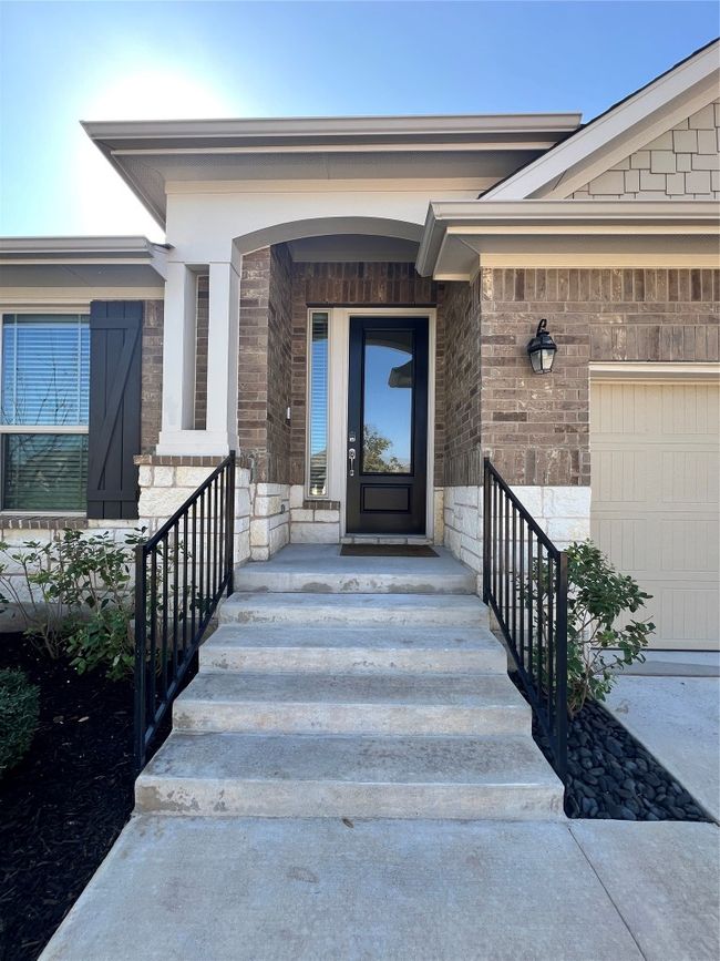 View of exterior entry featuring stone siding and a garage | Image 5