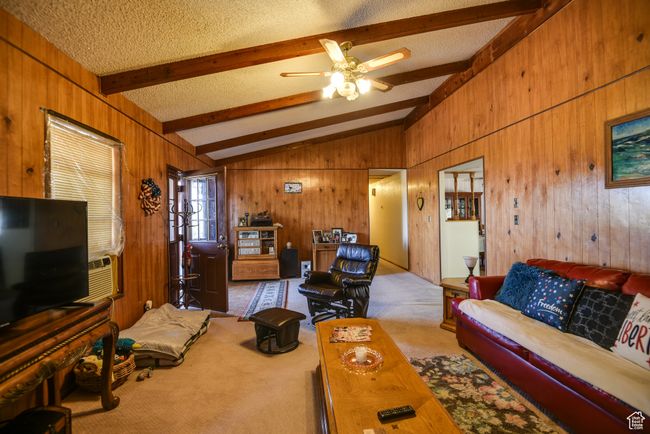 Carpeted living area with wooden walls, a textured ceiling, and ceiling fan | Image 24