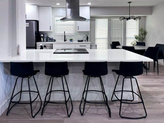 Kitchen with white cabinetry, island exhaust hood, appliances with stainless steel finishes, and an inviting chandelier | Image 4
