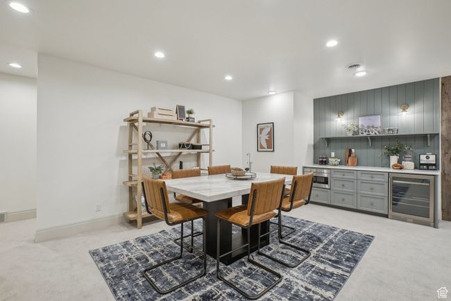 Dining room featuring light carpet, beverage cooler, visible vents, a bar, and recessed lighting | Image 40
