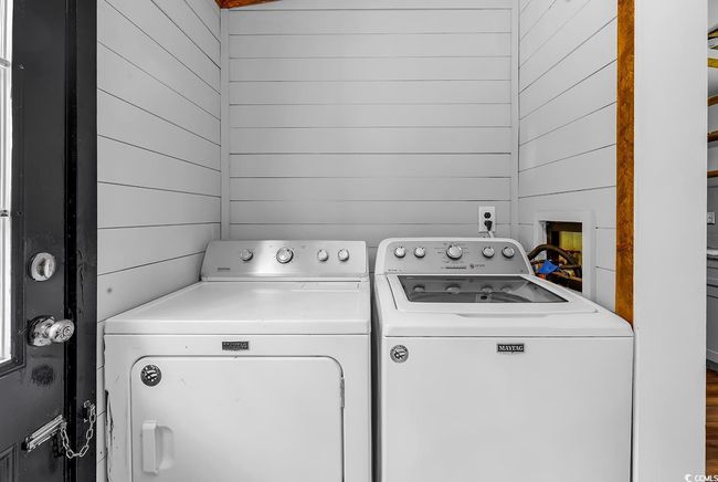 Laundry room featuring washing machine and dryer and wooden walls | Image 9