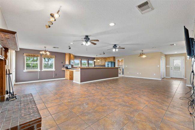 Unfurnished living room featuring a ceiling fan, recessed lighting, dark tile patterned floors, a chandelier, and rail lighting | Image 6