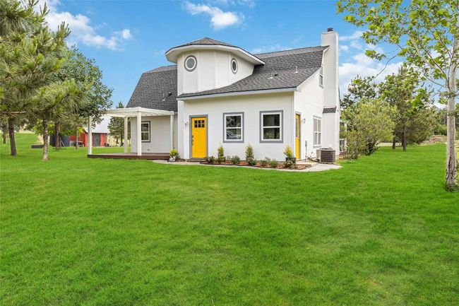 Rear view of house with stucco siding, a chimney, a yard, roof with shingles, and a patio area | Image 5